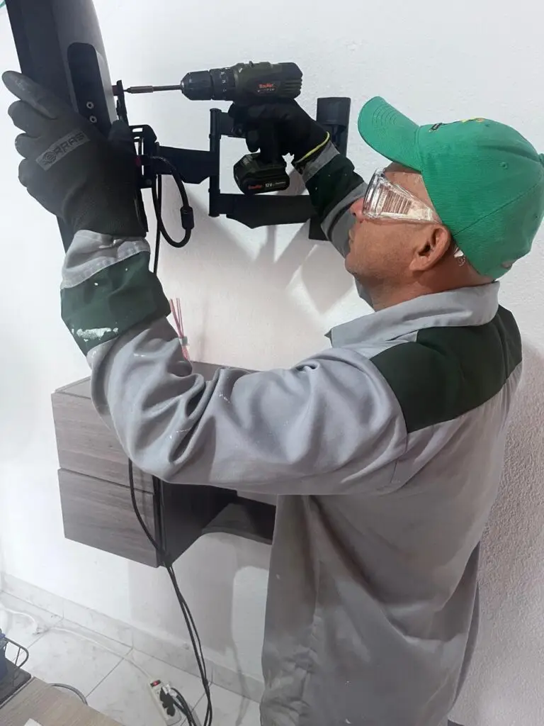 Técnico de Control S.A.S. instalando con taladro un soporte de televisor en la pared