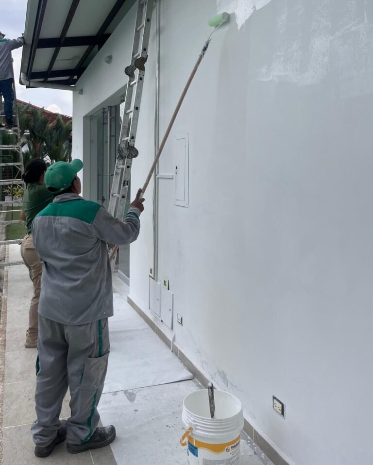 Técnico de Control S.A.S. pintando con rodillo de extensión el muro exterior de una vivienda